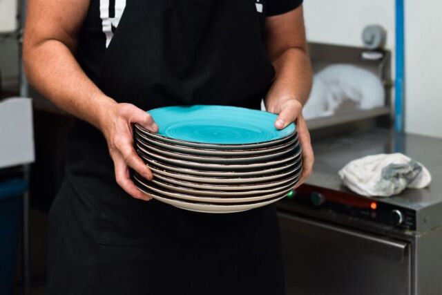 restaurant-kitchen-employee-carrying-stack-of-clea-2022-11-14-06-05-37-utc (1) (2)